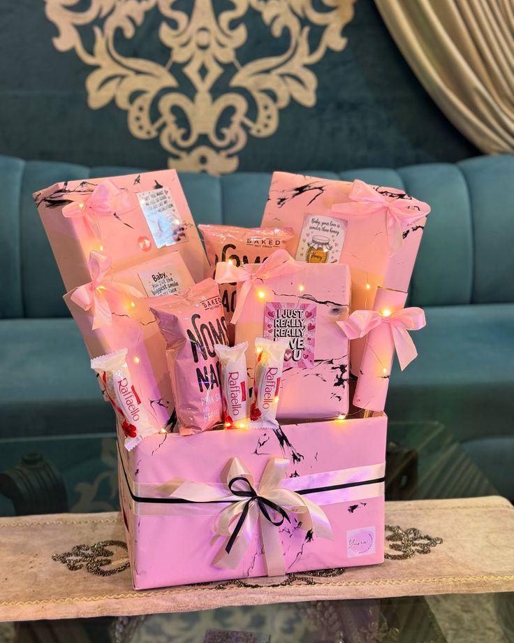 Pink gift basket with snacks and decorative elements on a table.